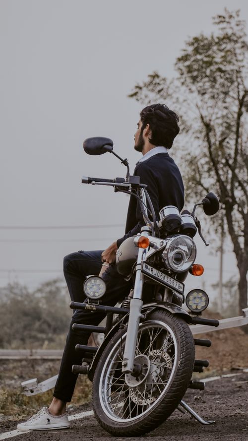 Free A stylish man sits on a classic motorcycle in an outdoor setting, reflecting a moment of relaxation. Stock Photo