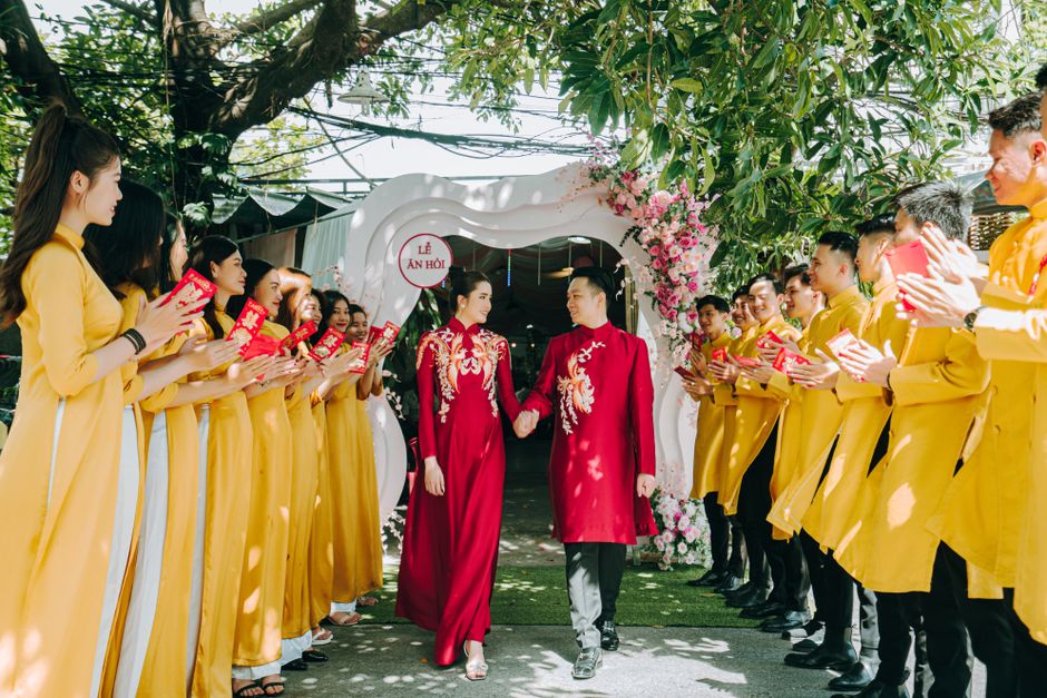 A couple in traditional Vietnamese attire celebrates their wedding with friends and family.