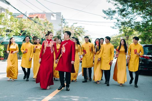 Asian wedding party celebrating outdoors in colorful traditional attire. Bright and joyful moment.