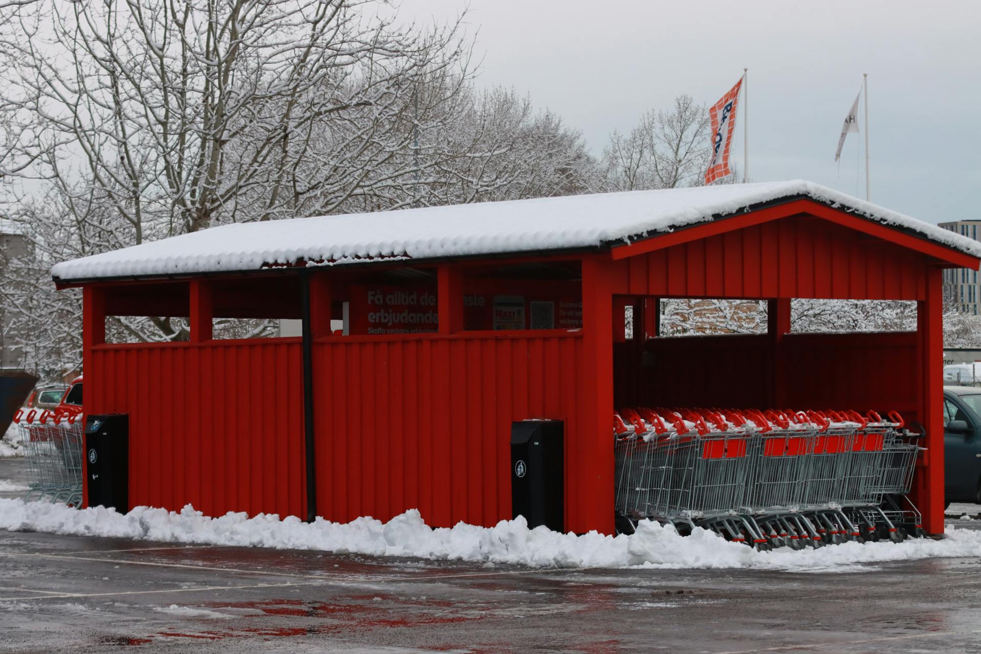 A red pavilion storing shopping carts covered with snow on a winter day.