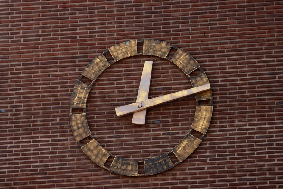 Close-up of a vintage clock mounted on a brick wall, showcasing classic design.