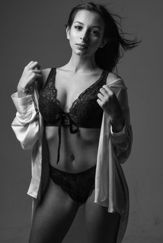 Stylish model posing in lace lingerie with open shirt, captured in a dramatic black and white studio shot.