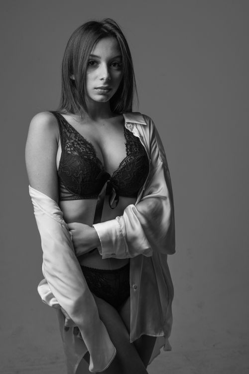 Free Black and white portrait of a woman in lingerie with a relaxed pose in a studio setting. Stock Photo