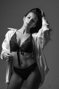 Stylish black and white portrait of a woman in lingerie with a confident pose and expression.