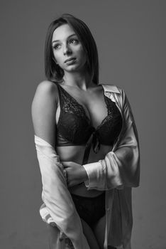 Black and white studio portrait of a woman in elegant lingerie with a soft expression.