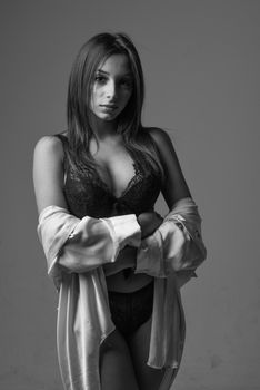 Portrait of a woman posing confidently in black lingerie and silk robe.