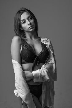 Black and white portrait of a woman posing in lingerie during a studio photoshoot.