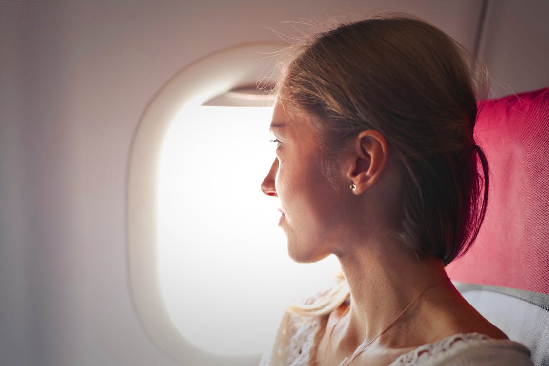 Free Selective Focus Photo of Woman Sitting on Chair Looking Outside Window on Plane Stock Photo