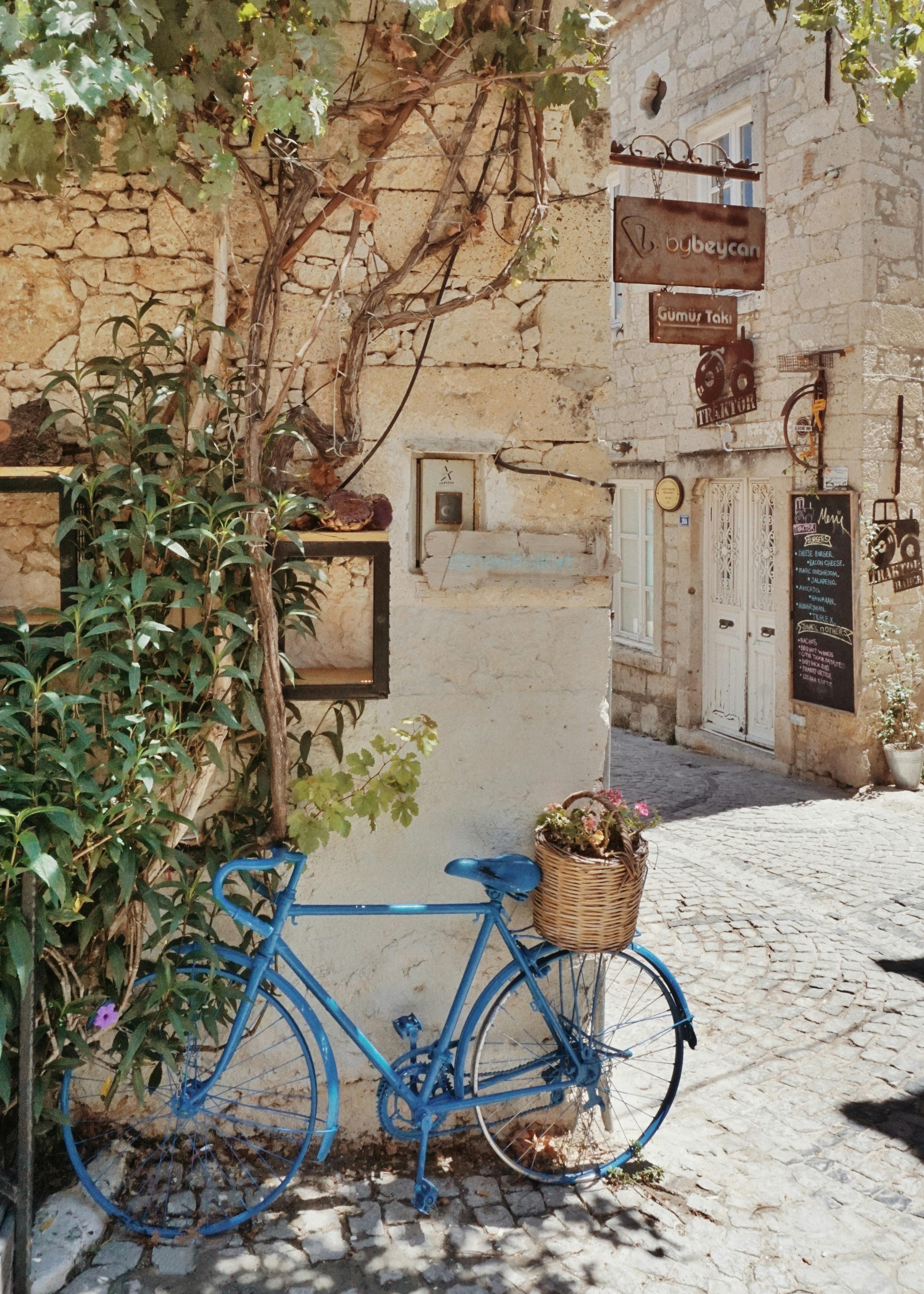 A scenic view of a blue bicycle on a quaint cobblestone street in Alaçatı, Turkey.