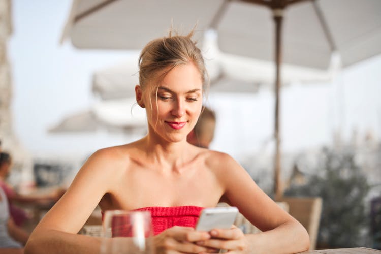 Woman Sitting On Chair While Holding Smartphone