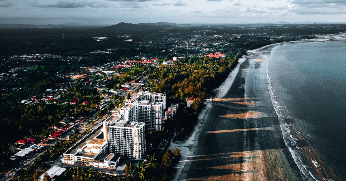 A stunning aerial photograph capturing the coastline of Kuantan, Malaysia, with sprawling buildings and lush greenery.