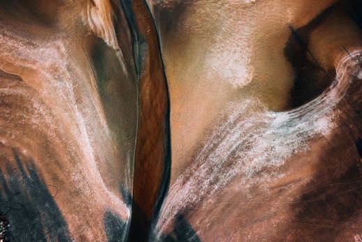 Aerial abstract of tidal channel patterns on a coastline — photo by Pok Rie on Pexels