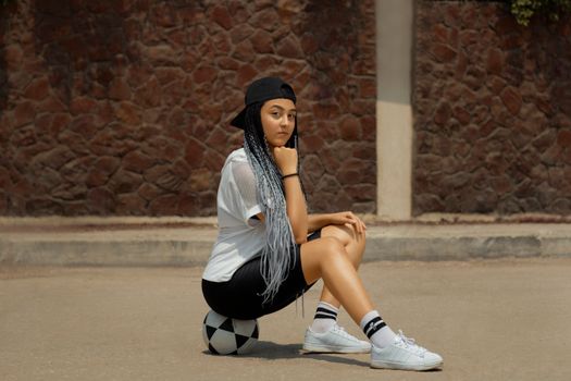 Portrait of a fashionable young woman in casual attire and braids outdoors, exuding confidence.