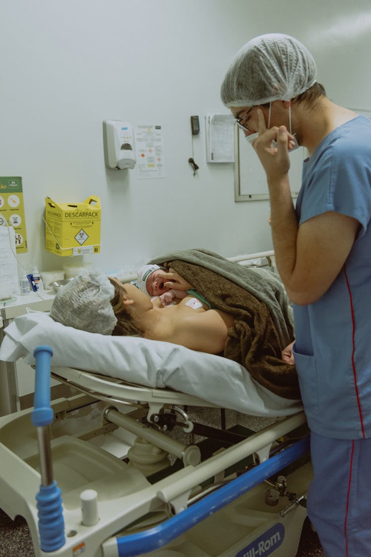 A Woman Holding A Newborn Baby In Delivery Room