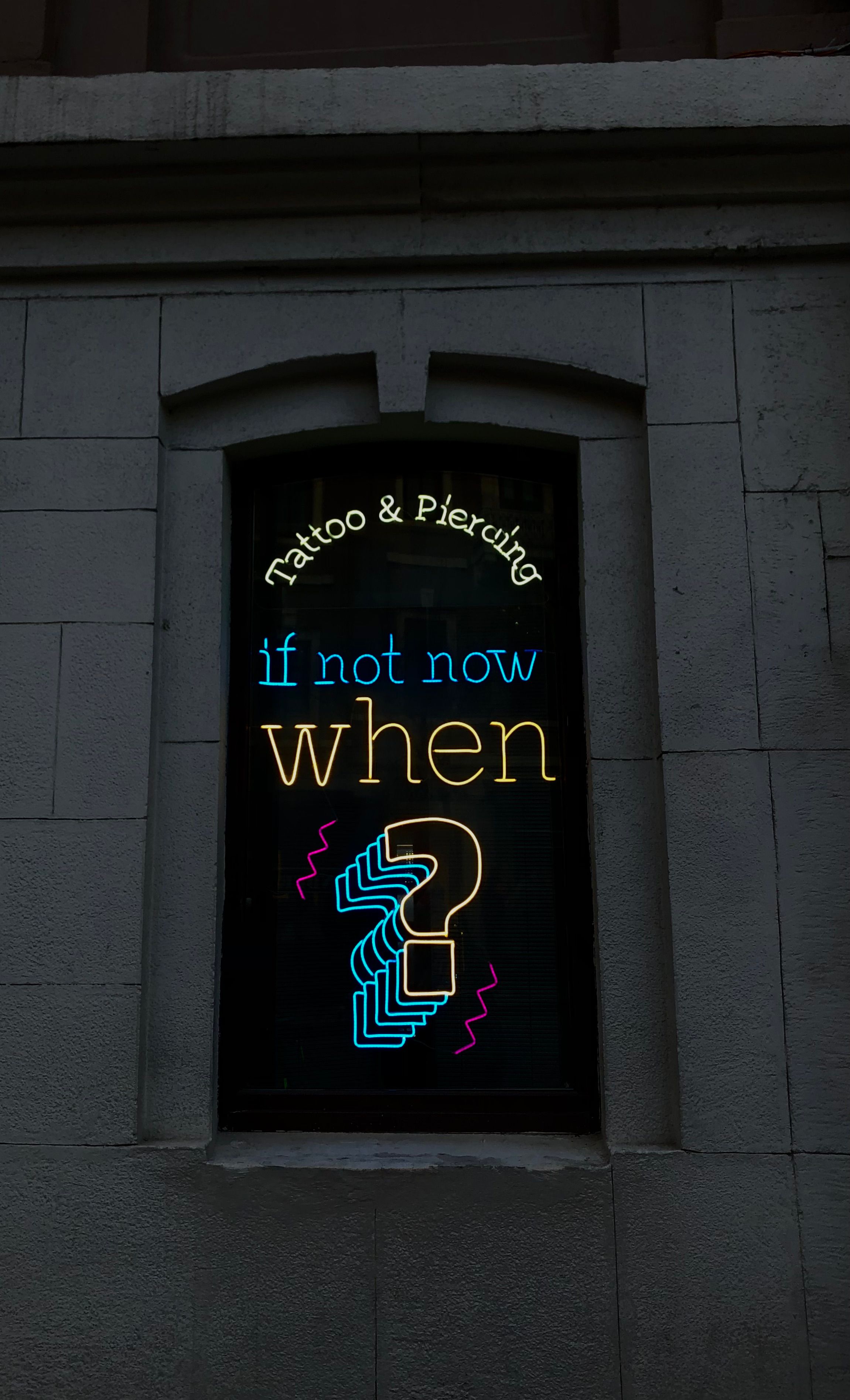Neon sign for a tattoo and piercing shop in İstanbul's urban setting.