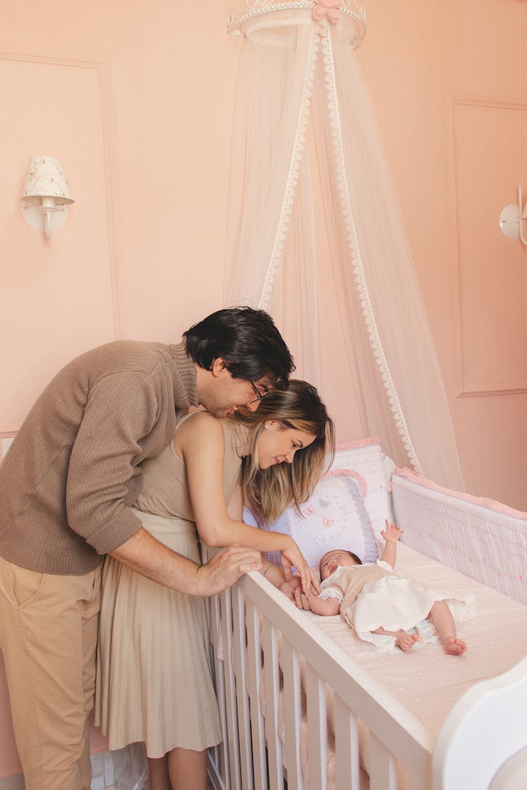 A Couple Standing Together Near Their Baby At The Crib