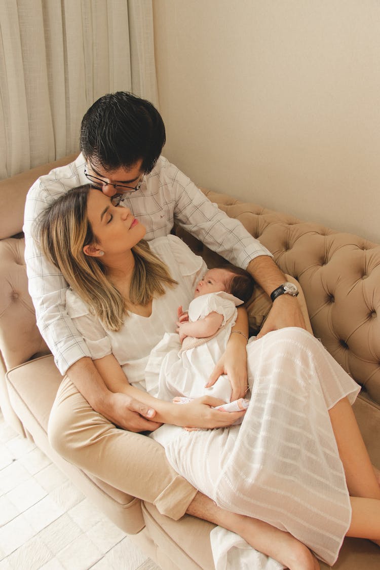 Young Parents With Newborn Baby On Sofa