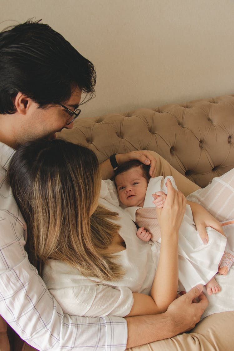 Man And Woman Cuddling On A Couch With Their Baby