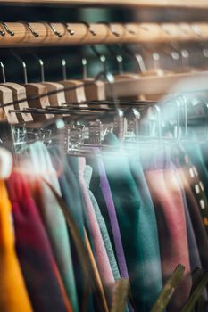 Vibrant clothing lined up on hangers behind a glass window, showcasing a modern retail store.