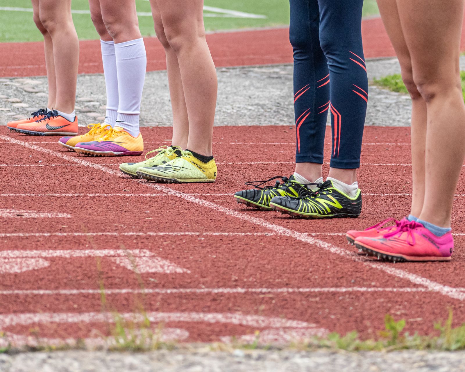 Runner adjusting a knee brace outdoors on a bright path