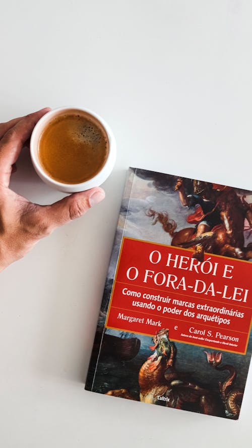 Cup of Coffee in Hand by Book