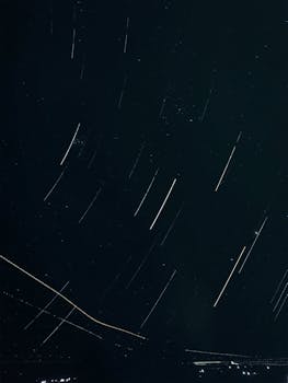 Dramatic long exposure photograph capturing star trails against a dark night sky, creating a mesmerizing effect.