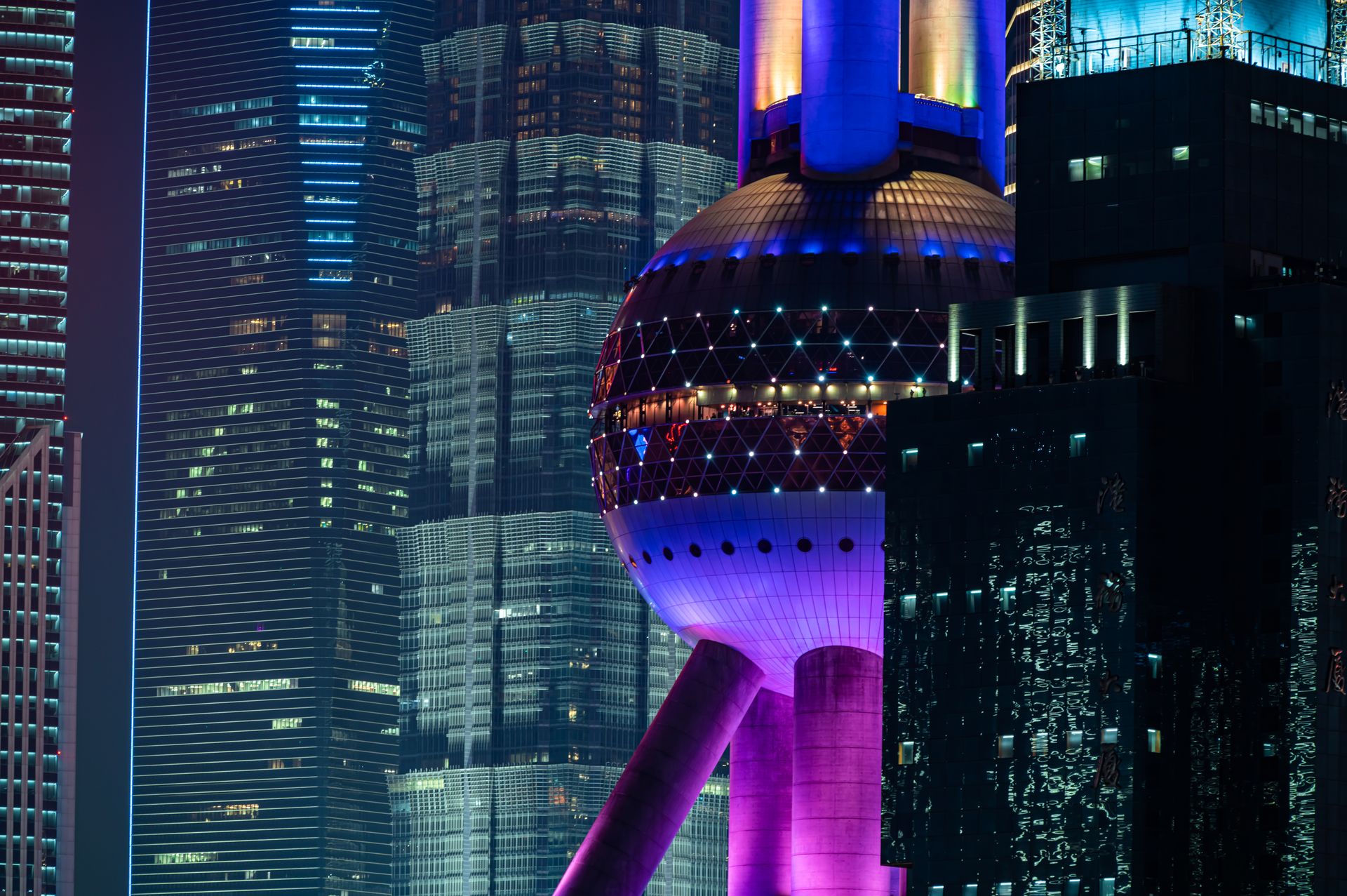 Vibrant night scene featuring the iconic Oriental Pearl Tower in Shanghai with illuminated skyscrapers.