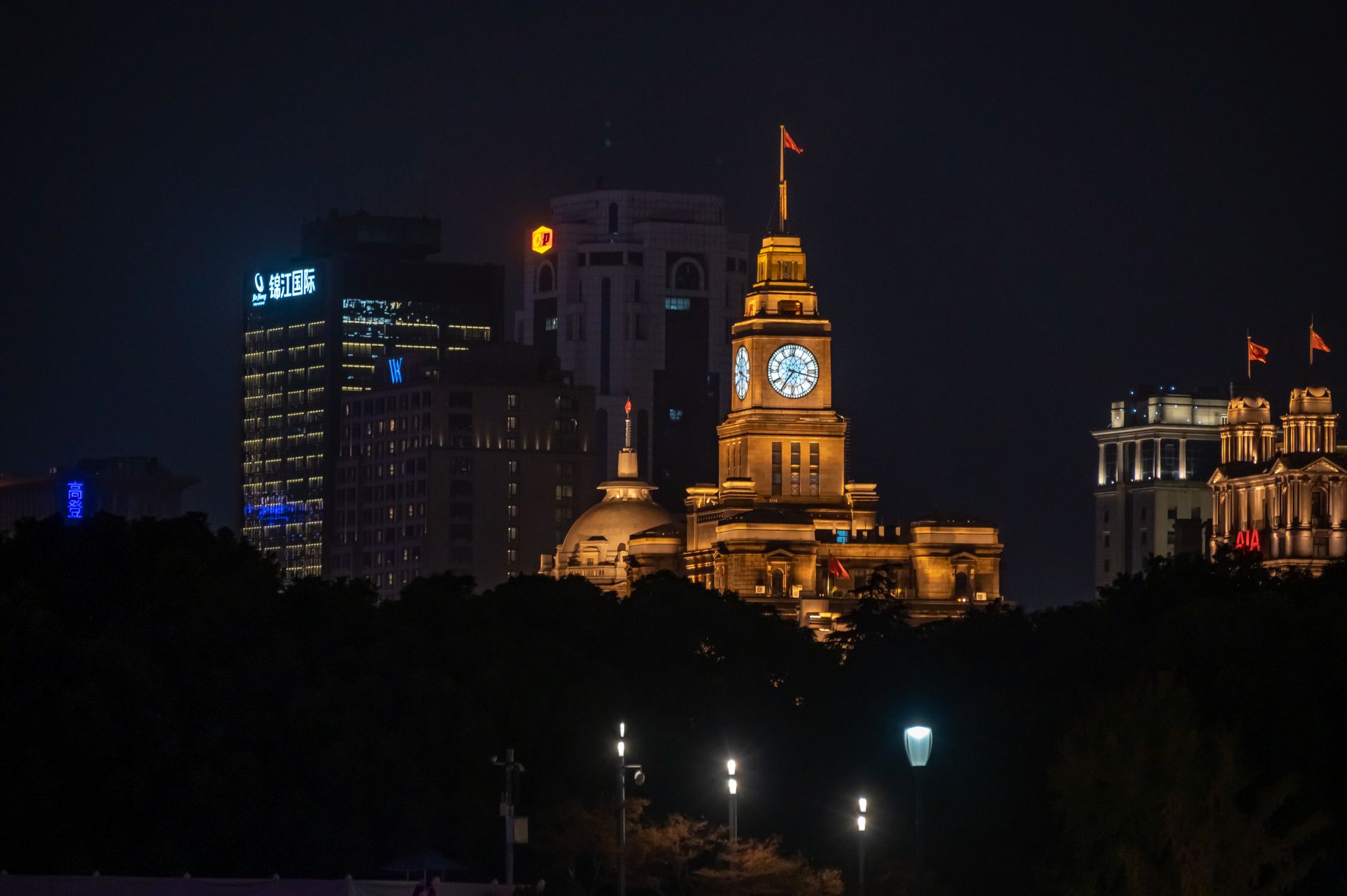 Stunning night view of The Bund skyline featuring the iconic illuminated clock tower in Shanghai, China.