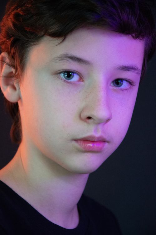 Free Close-up portrait of a teenager with colorful lighting against a black background. Stock Photo
