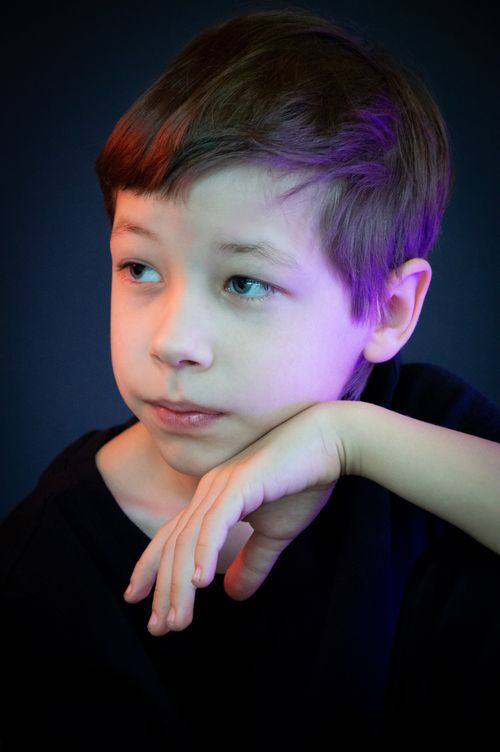 Free Close-up portrait of a thoughtful child in a studio setting with colorful lighting. Stock Photo