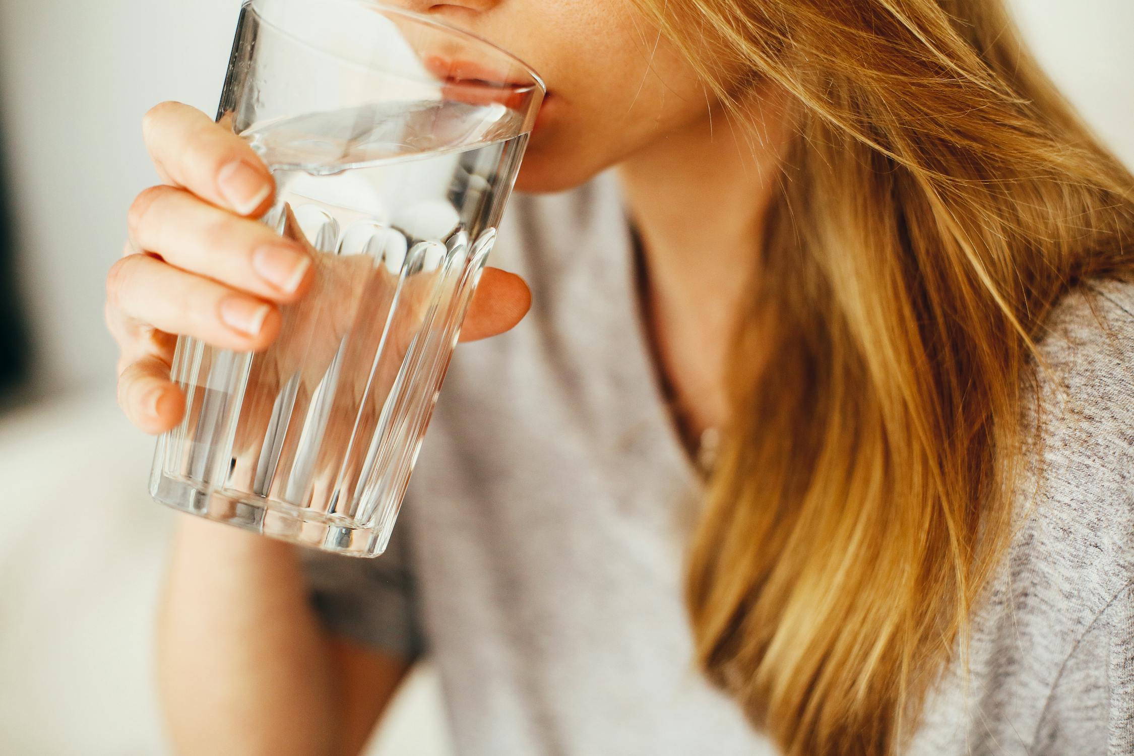 woman drinking water from clear glass