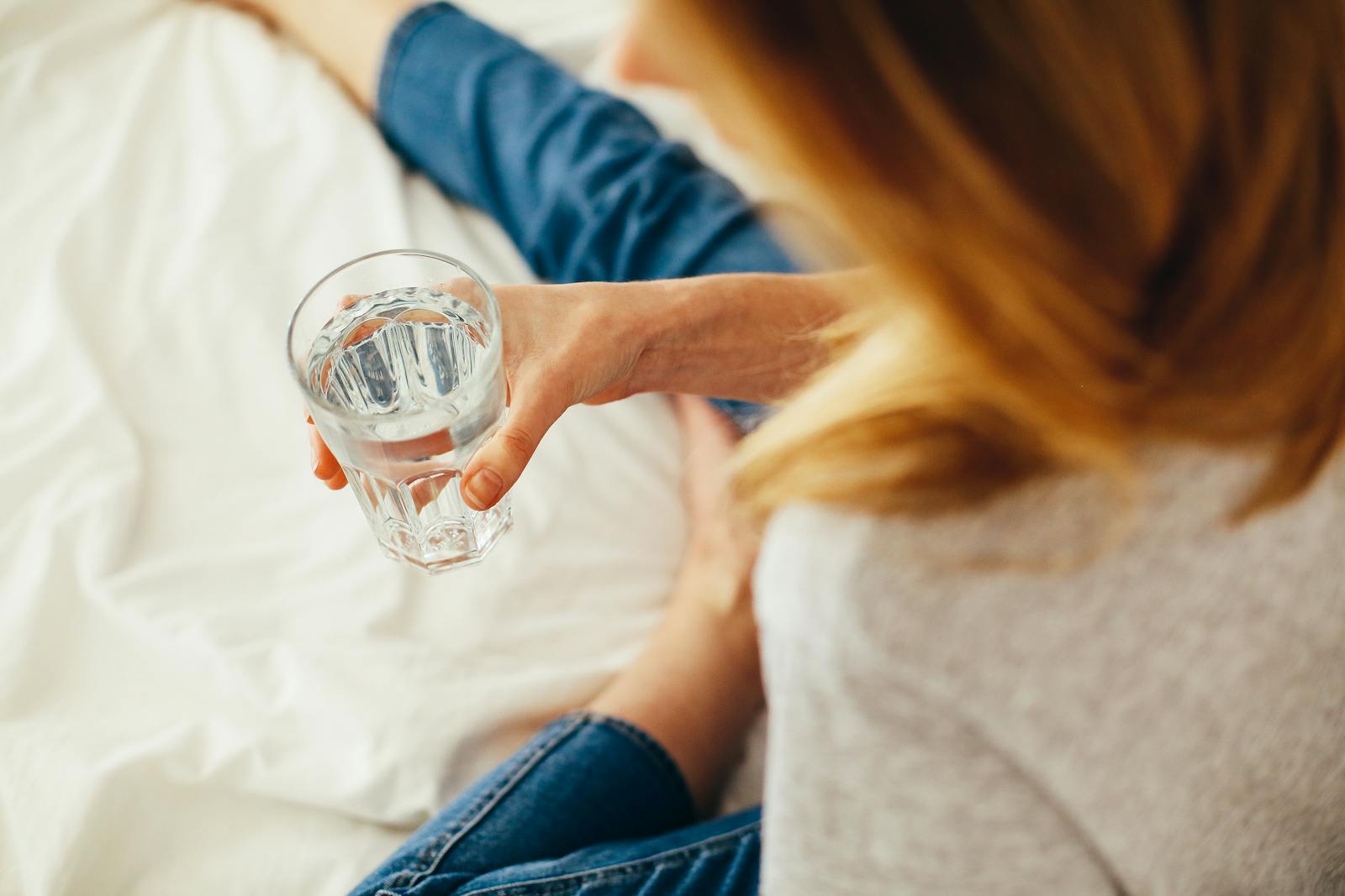Person pouring water into a glass on a kitchen counter