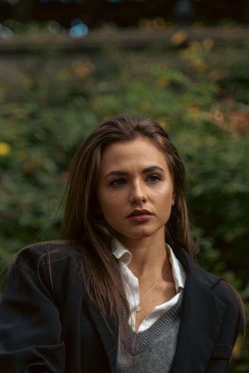 Free Portrait of a woman in a blazer, thoughtful expression, outdoors in New York City park. Stock Photo