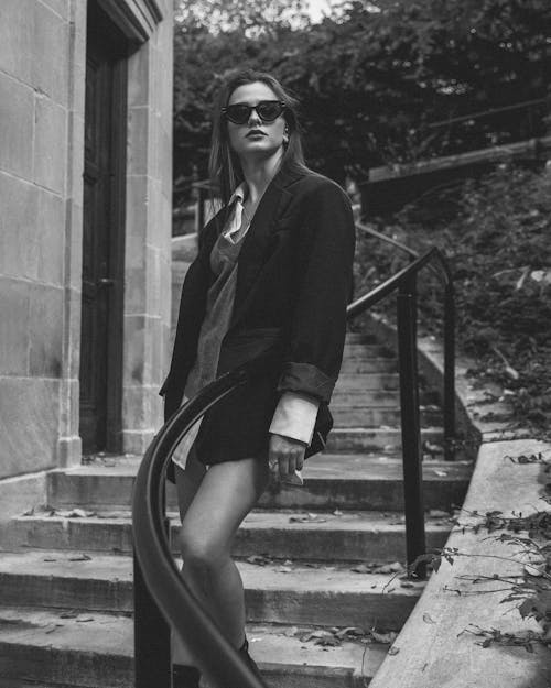 Grayscale Photo of a Woman in a Stylish Outfit and Sunglasses