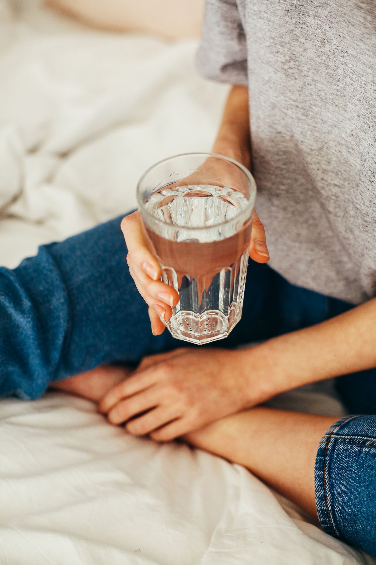 Woman drinking a glass of water in the kitchen in the morning