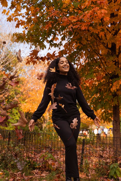 Woman in Black Long Sleeve Shirt Standing beside Brown Tree