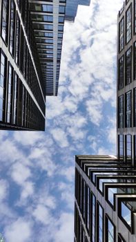 Looking up at modern skyscrapers in downtown Warszawa, capturing a dramatic view against a vibrant blue sky.
