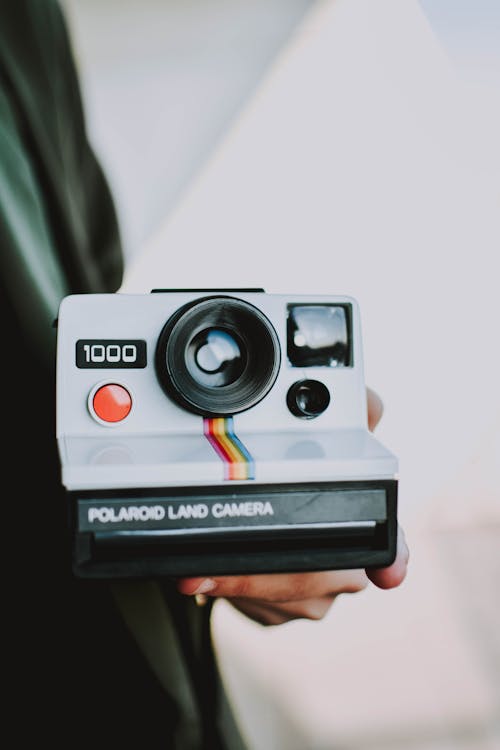 무료 회색 폴라로이드 랜드 카메라를 들고있는 사람 스톡 사진