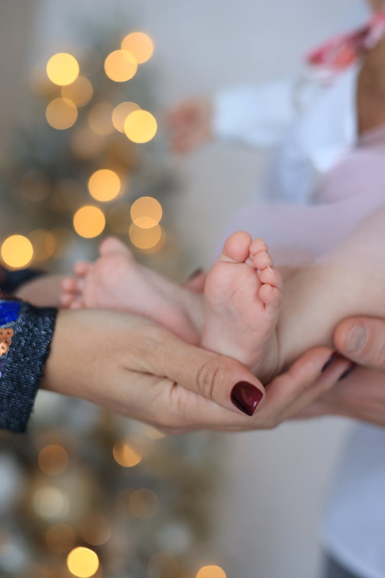 A Person Holding A Baby's Feet