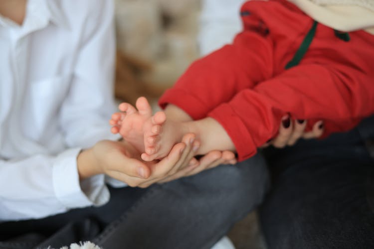 A Person Holding A Baby's Feet