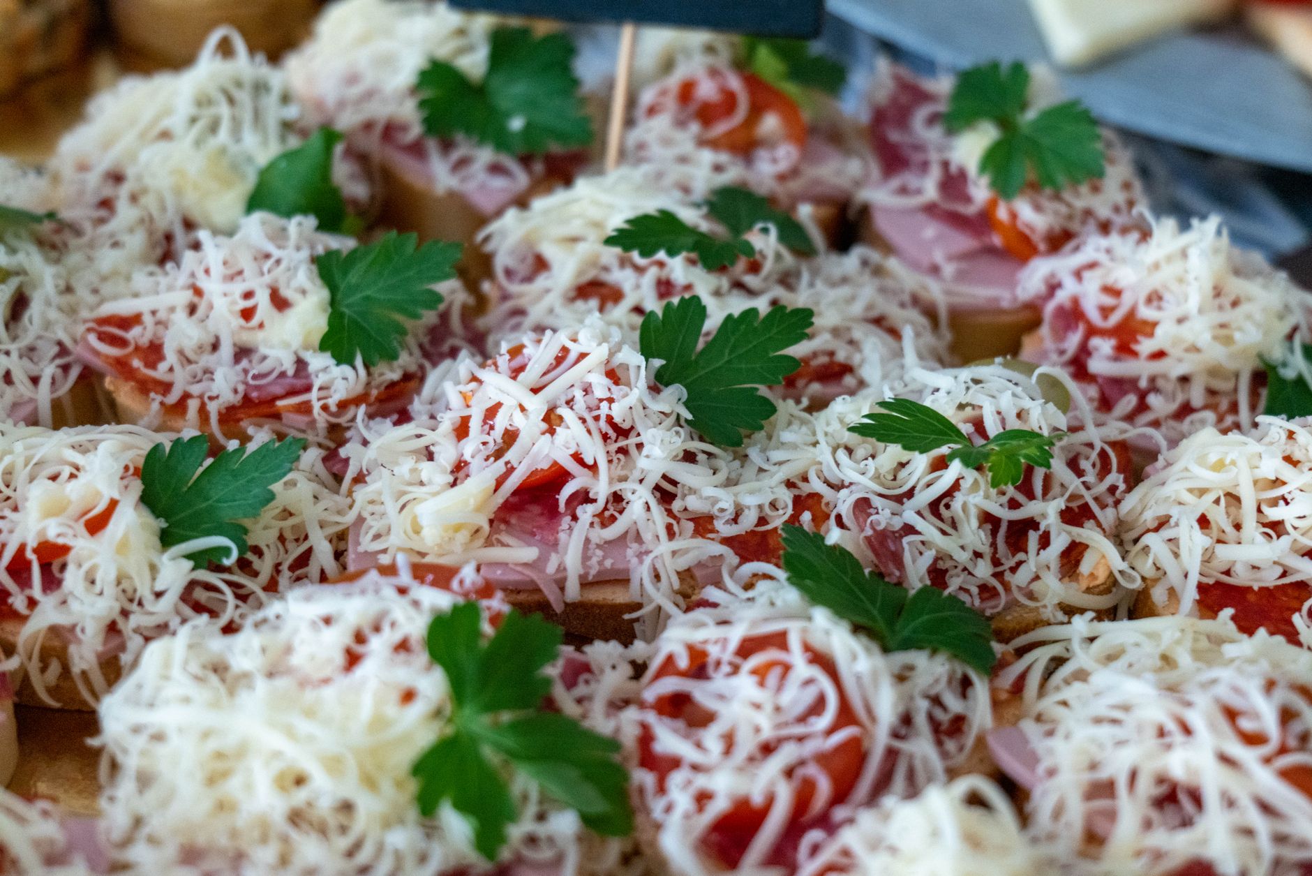 A mouth-watering display of finger foods topped with shredded cheese and parsley leaves, perfect for party snacks.