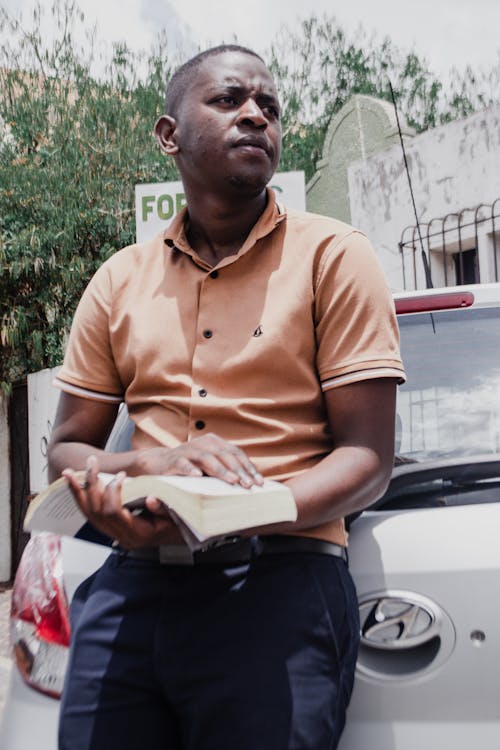 A Man in Brown Button-Up Shirt Holding a Book