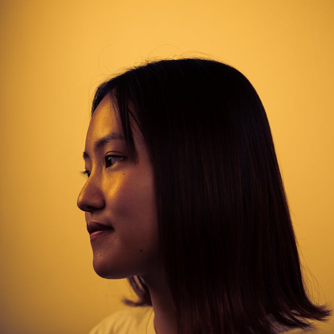 A side view portrait of an Asian woman with a warm, artistic lighting effect.