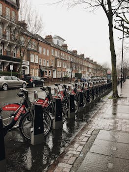 A line of rental bicycles on a wet residential street in London, England after rain.
