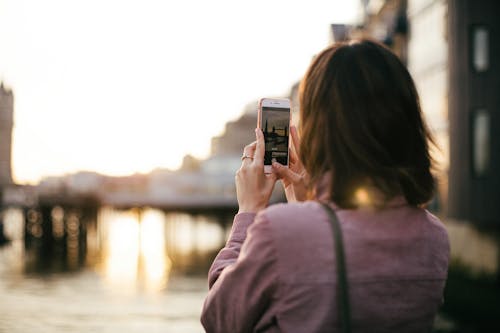無料 スマートフォンを保持している栗色の長袖シャツを着ている女性 写真素材