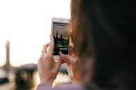 日落时分，一名妇女用智能手机拍摄伦敦的天际线