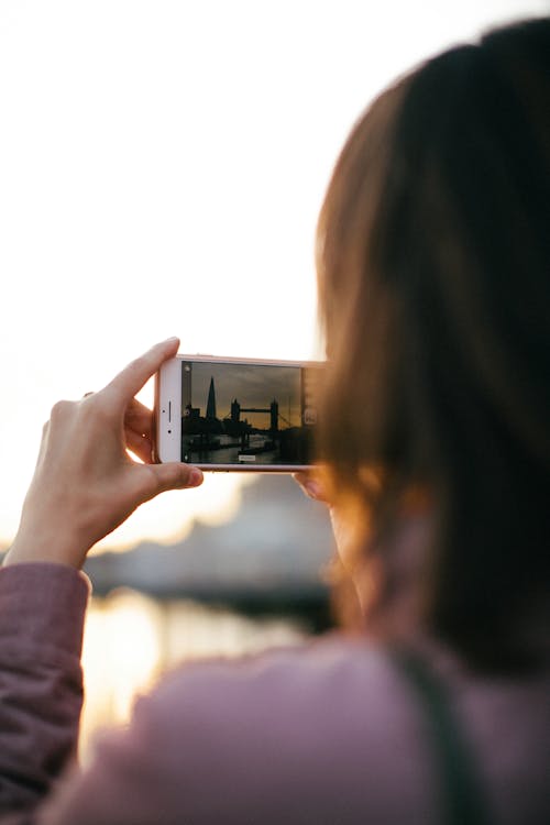 Persona In Possesso Di Smartphone Bianco Durante L'acquisizione Di Tower Bridge All'ora D'oro