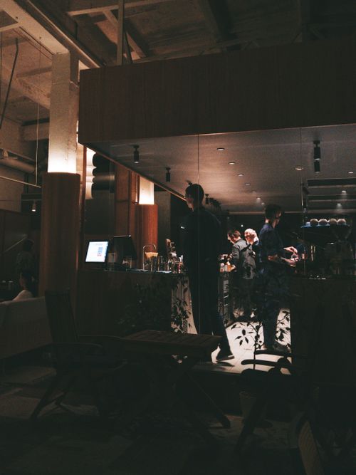 Free Warmly lit café interior with people interacting, creating a cozy evening ambiance. Stock Photo