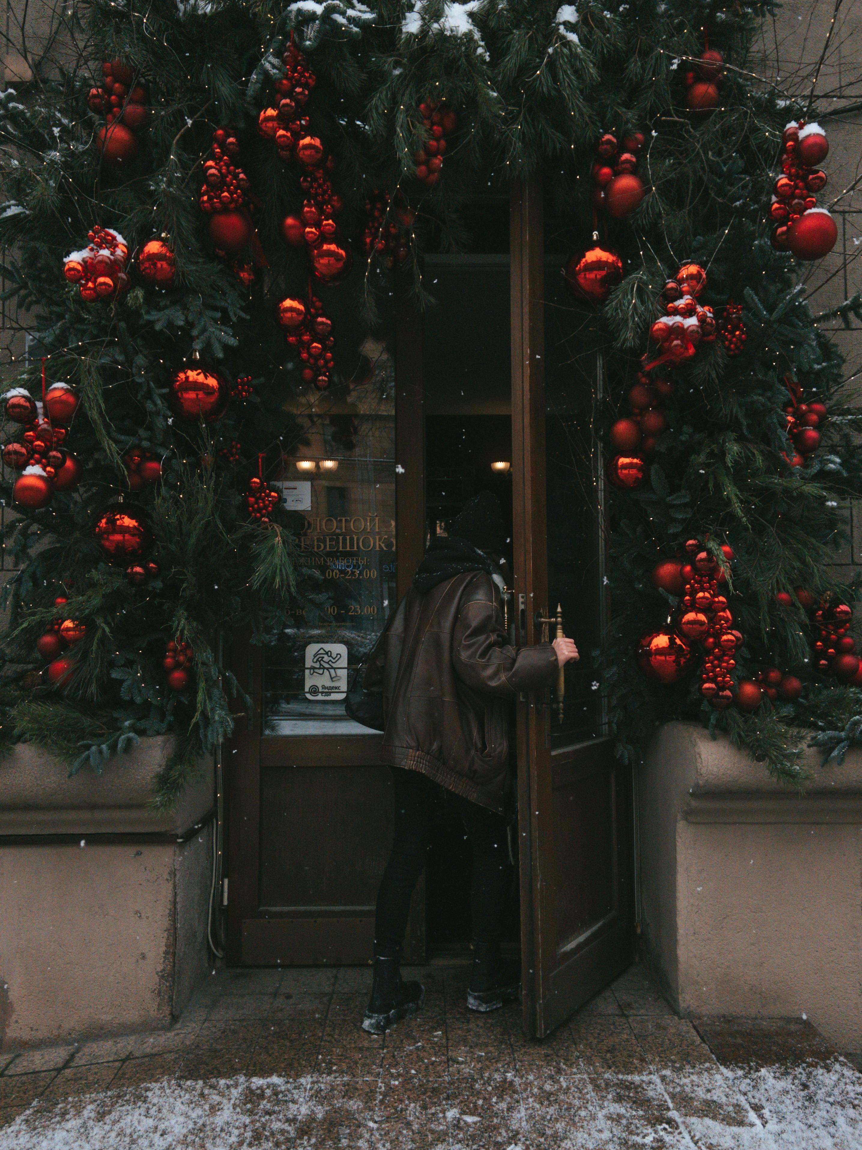 Entrance adorned with red Christmas baubles and green garlands, exuding a cozy winter holiday vibe.