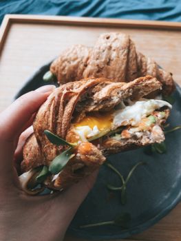 Savor a delicious croissant filled with fresh egg and veggies, perfect for a hearty breakfast.